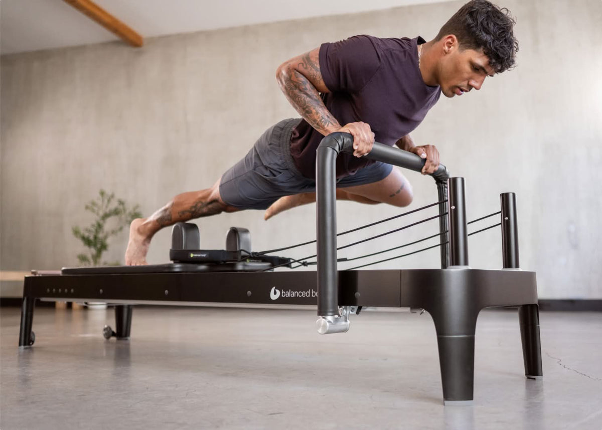 Zwarte Balanced Body Pilates reformer met Signature Springs en walnut standing platform