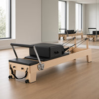 The Maple Studio Black Edition: esdoornhouten pilates reformer met zwarte bekleding in een lichte pilatesstudio