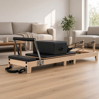 The Oak Foldable Black Edition: houten pilates reformer van eikenhout met zwarte bekleding in een lichte woonkamer, ideaal voor pilates thuis