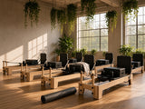 Pilatesstudio ingericht met meerdere Wood Reformer The Oak Studio Black Edition reformers van eikenhout met zwarte bekleding