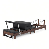 Wood Reformer The Walnut Foldable Black Edition – inklapbare pilates reformer van walnotenhout met zwarte bekleding, productfoto op witte achtergrond