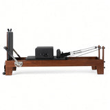 Wood Reformer The Walnut Studio Black Edition – pilates reformer van walnotenhout met zwarte bekleding en rugleuning, zijaanzicht op witte achtergrond