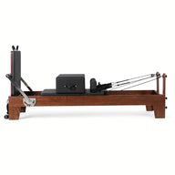 Wood Reformer The Walnut Studio Black Edition – pilates reformer van walnotenhout met zwarte bekleding en rugleuning, zijaanzicht op witte achtergrond