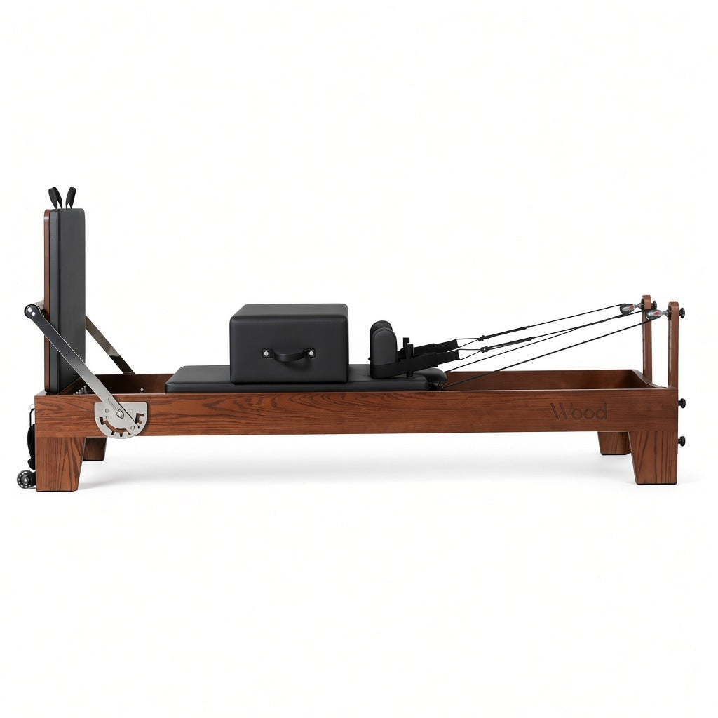 Wood Reformer The Walnut Studio Black Edition – pilates reformer van walnotenhout met zwarte bekleding en rugleuning, zijaanzicht op witte achtergrond