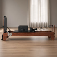 The Walnut Studio Black Edition: walnotenhouten pilates reformer met zwarte bekleding en rugleuning in een lichte studio