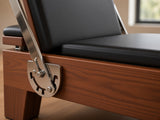 Close-up van de Wood Reformer The Walnut Studio Black Edition: walnotenhouten frame, rvs voetbalkverstelling en zwarte bekleding